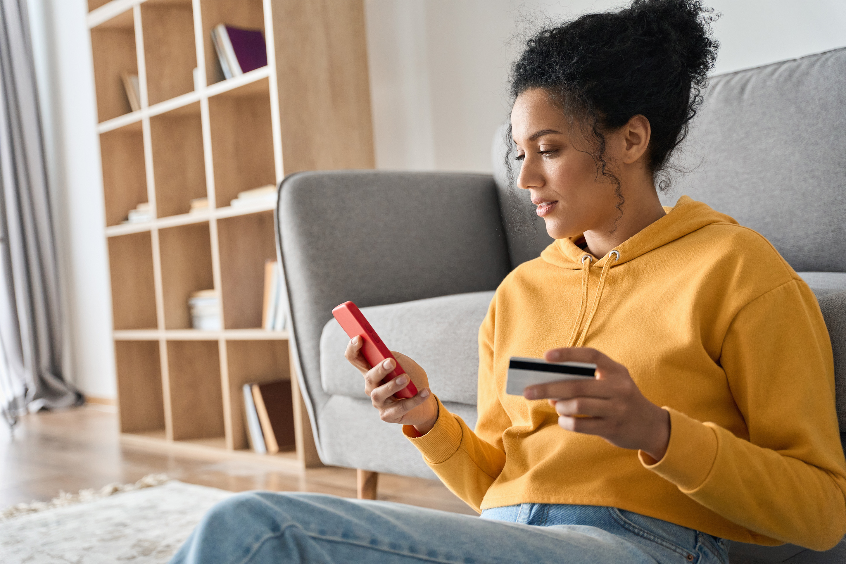 Woman doing banking on her phone while sitting on couch.