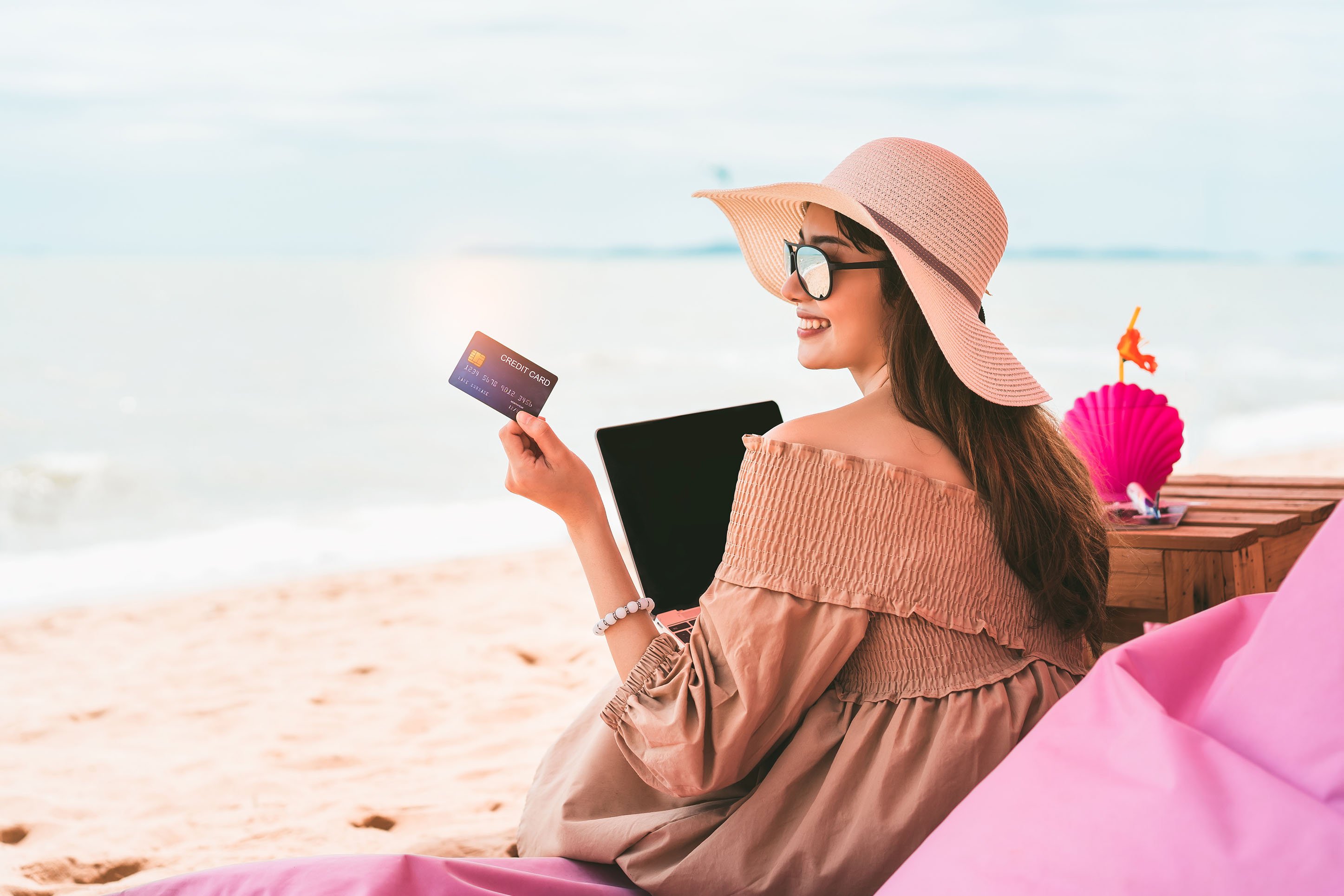 Woman on a beach, paying with a credit card. 