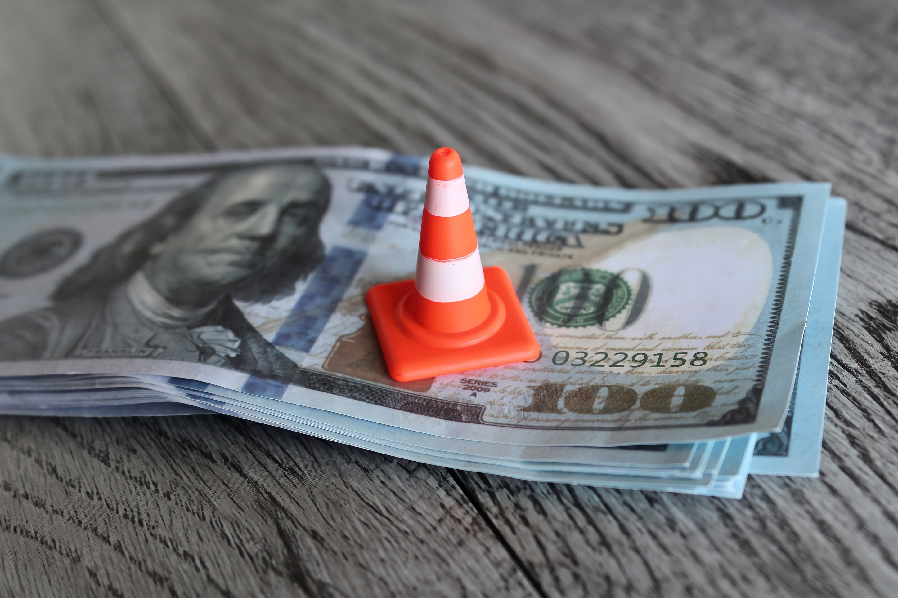 Stack of cash with a traffic cone on top. 