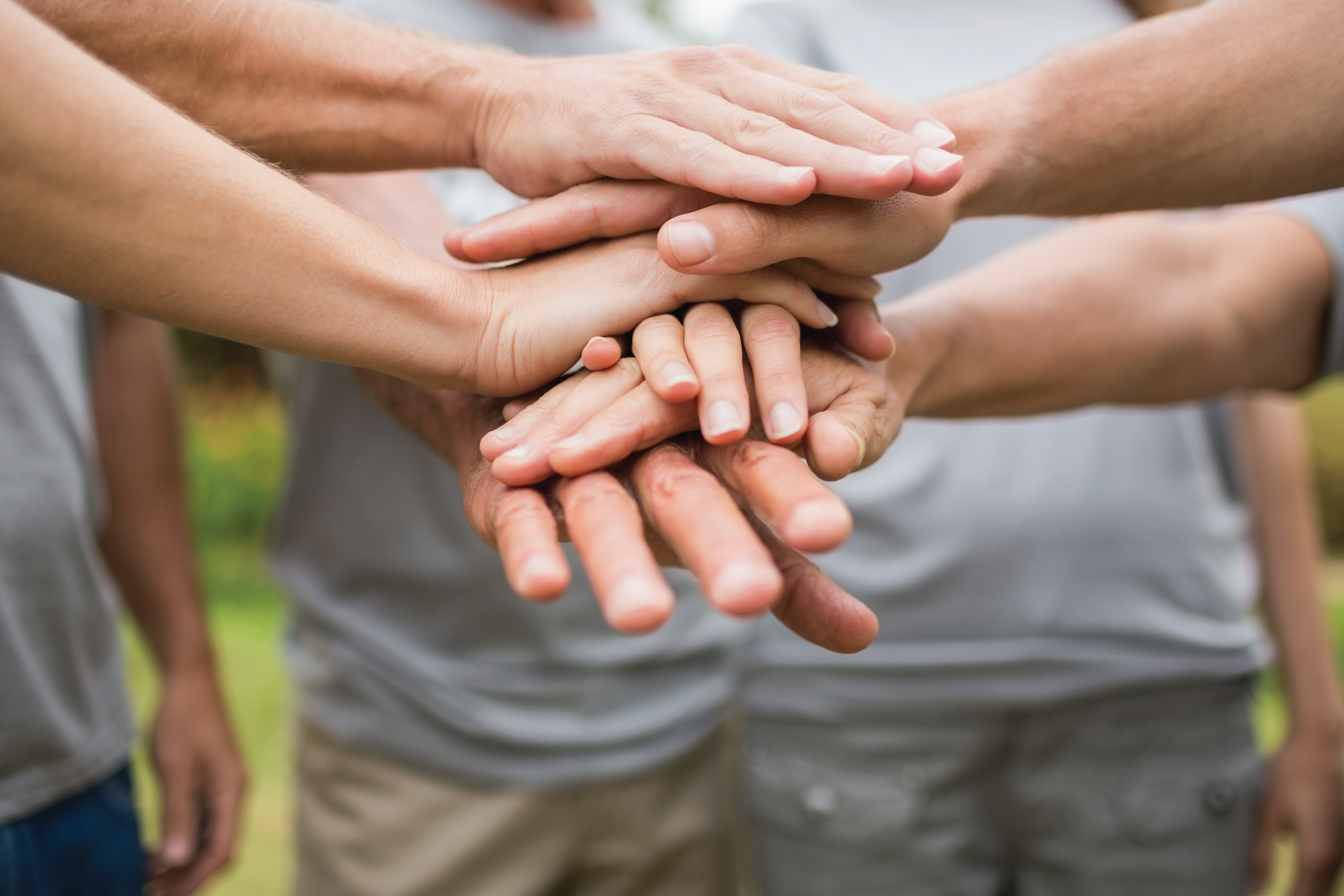 people putting their hands together in a huddle to show teamwork