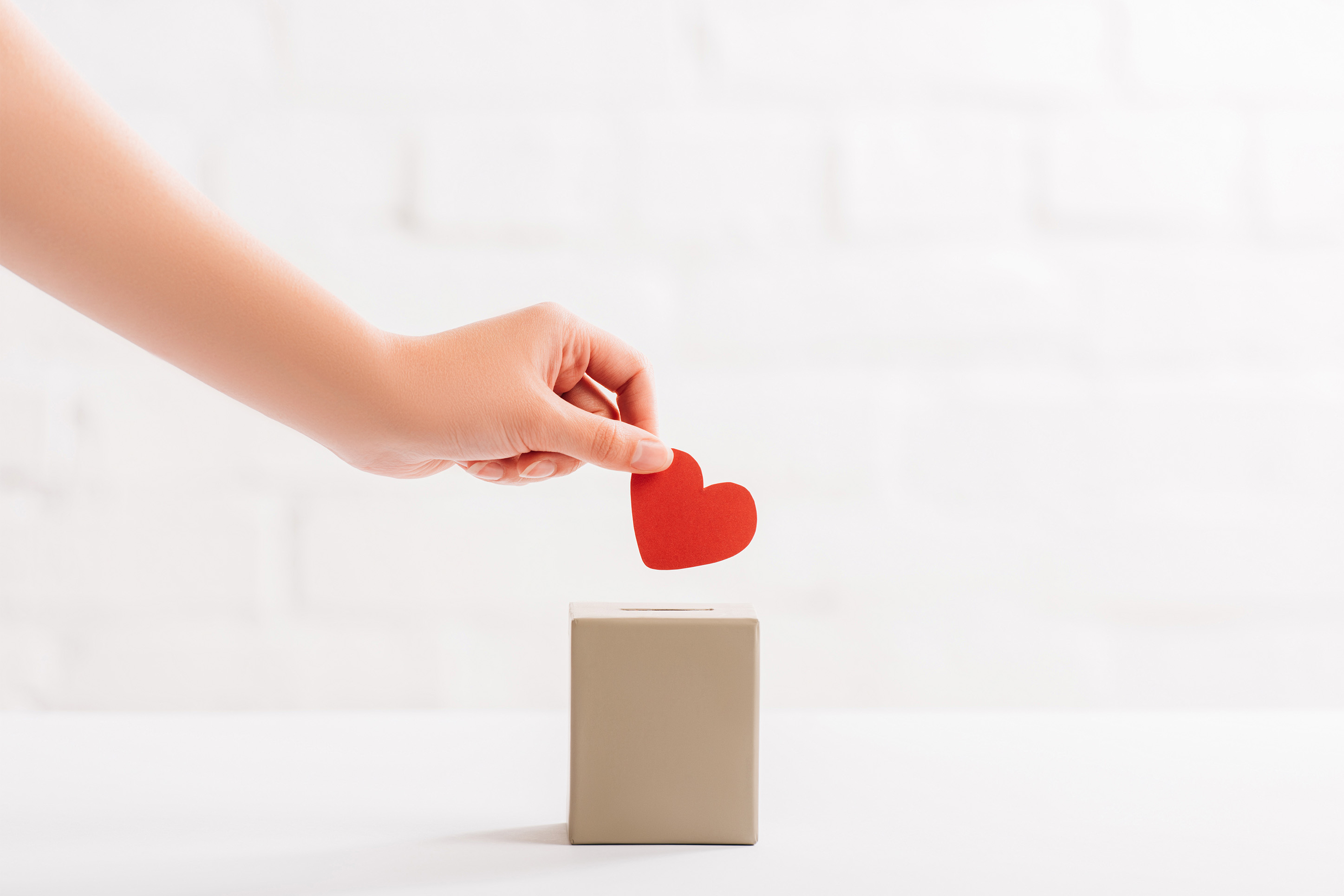 Photo of someone dropping a heart into a piggy bank. 
