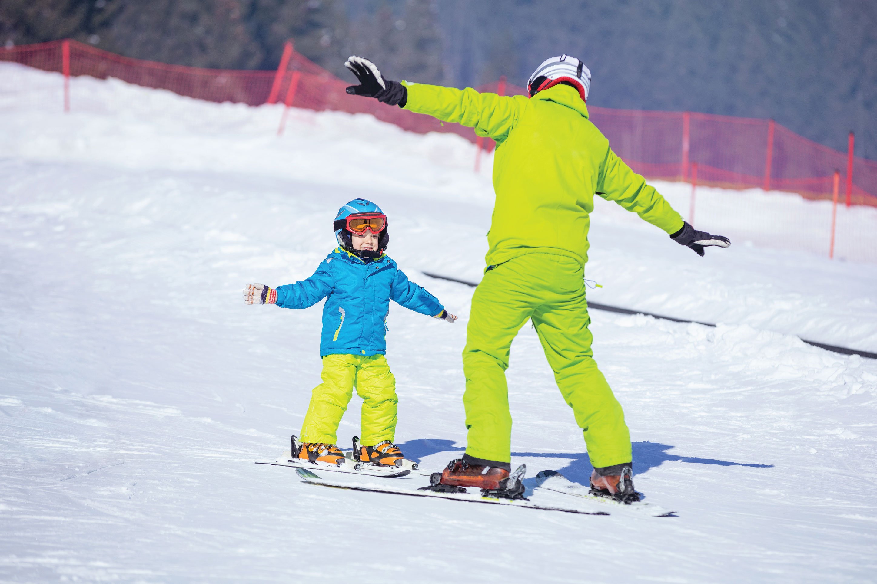 father teaching his son to snowboard