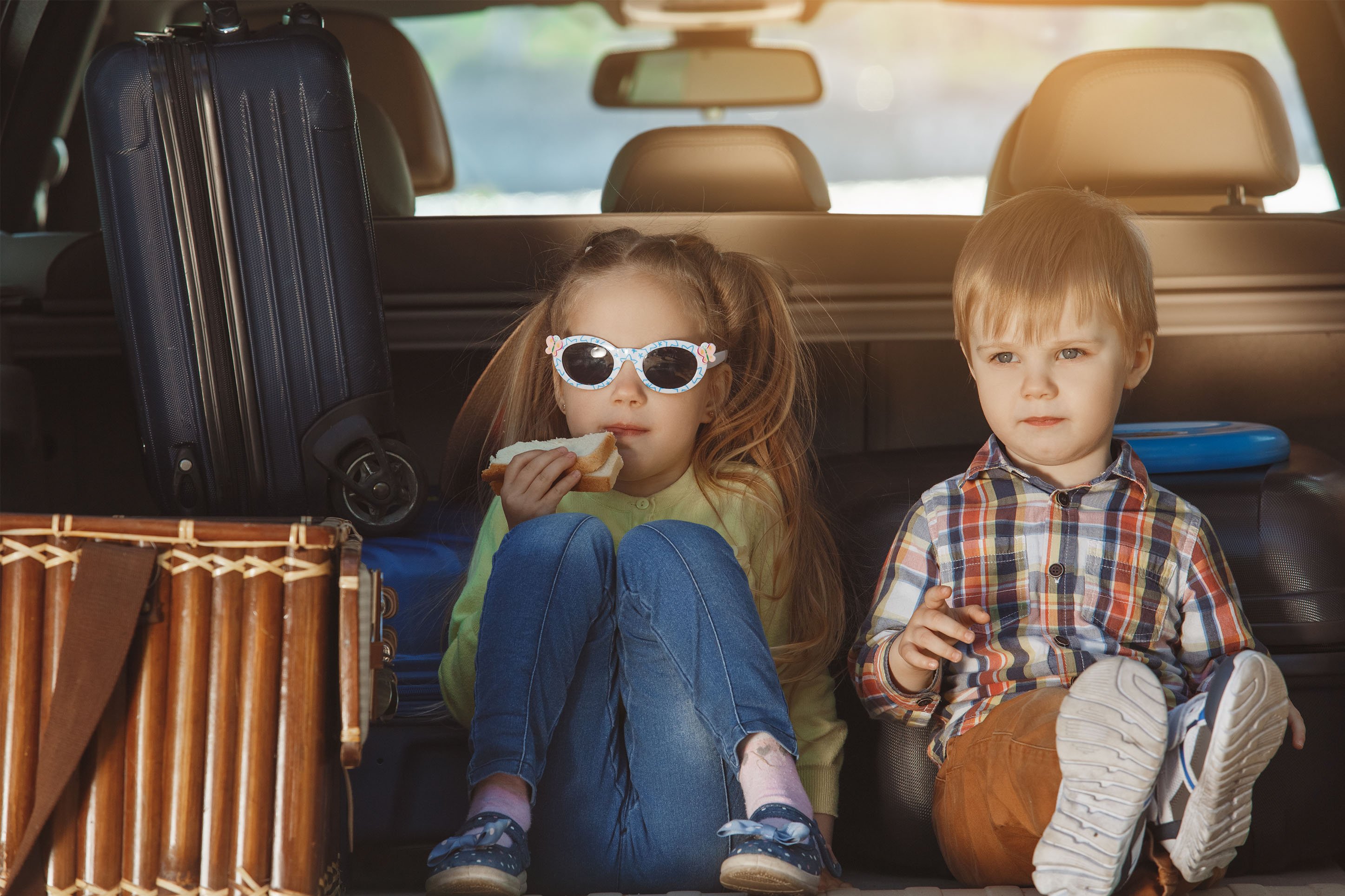 Kids eating snacks in the back of the car. 