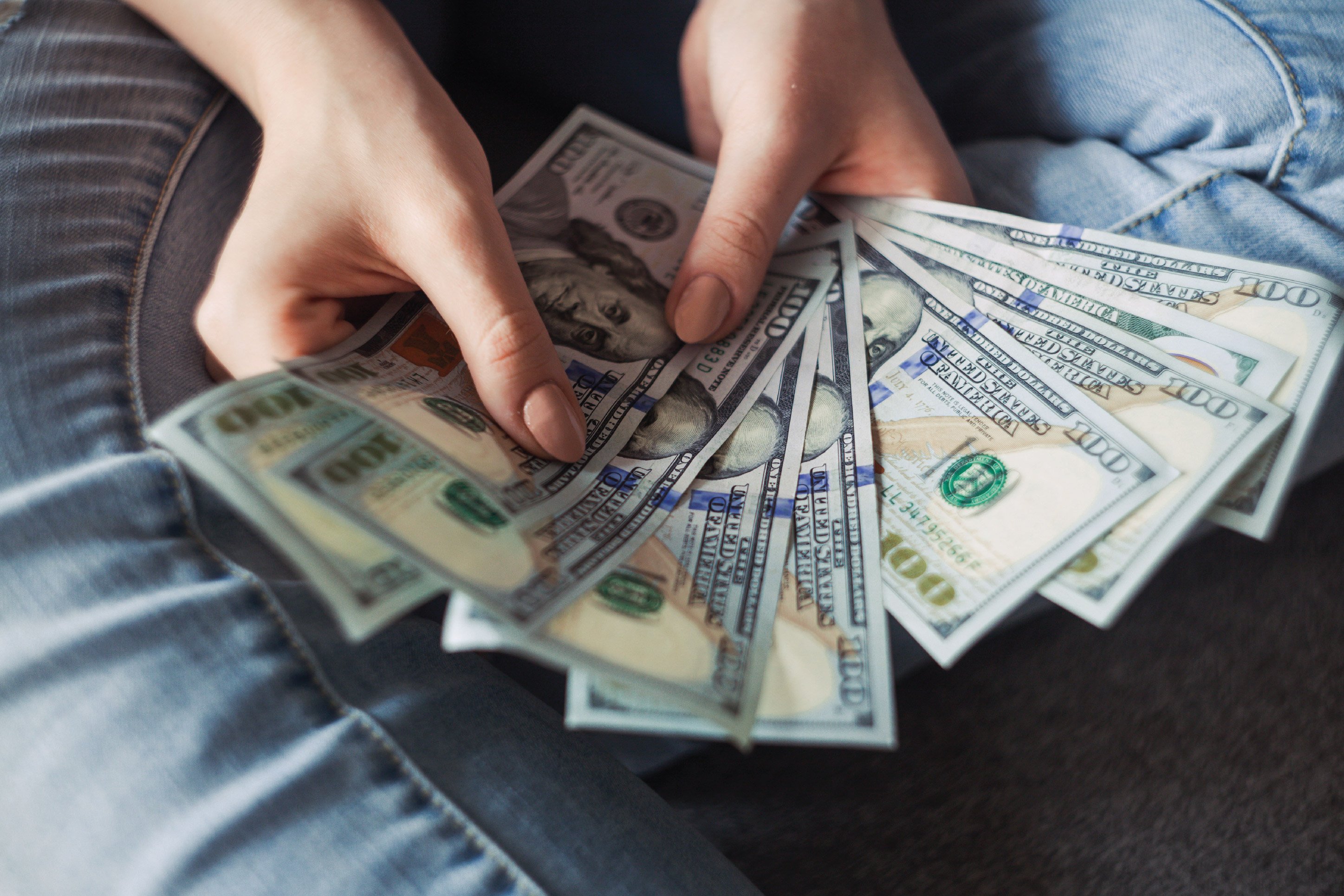 woman holding one hundred dollar bills
