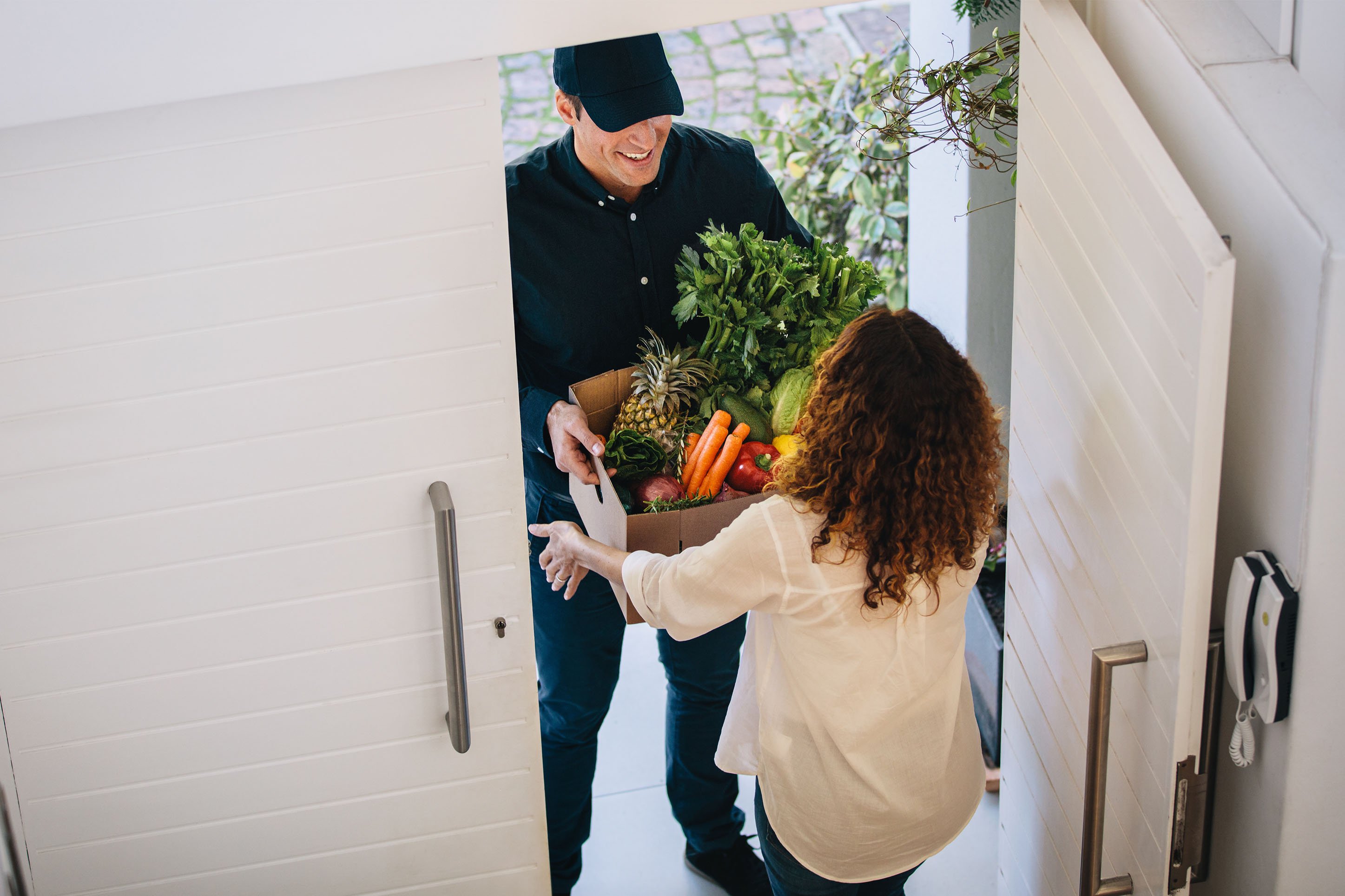 Man delivering groceries to a woman's home. 