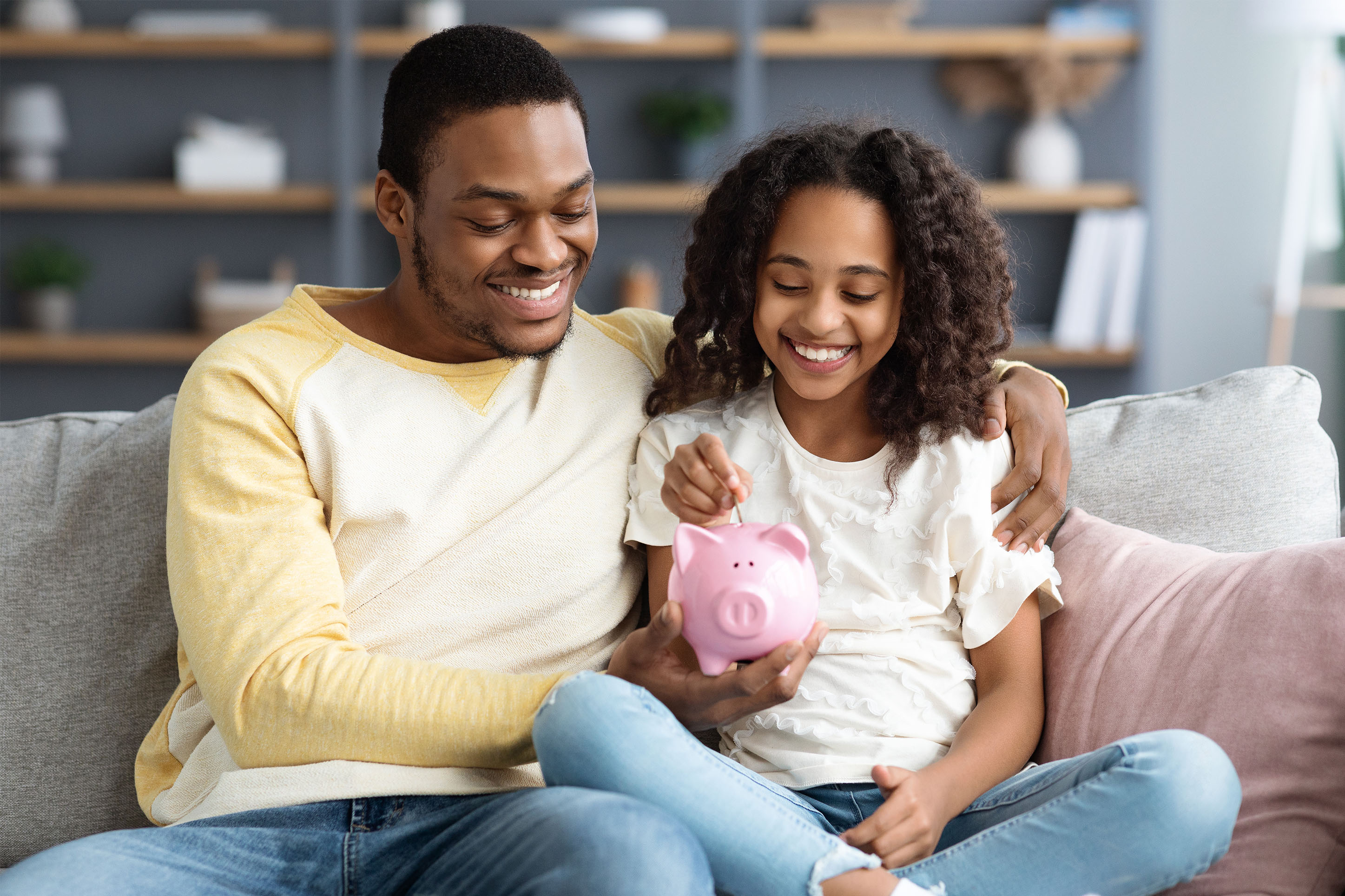 Father and daughter putting money into a piggy bank. 