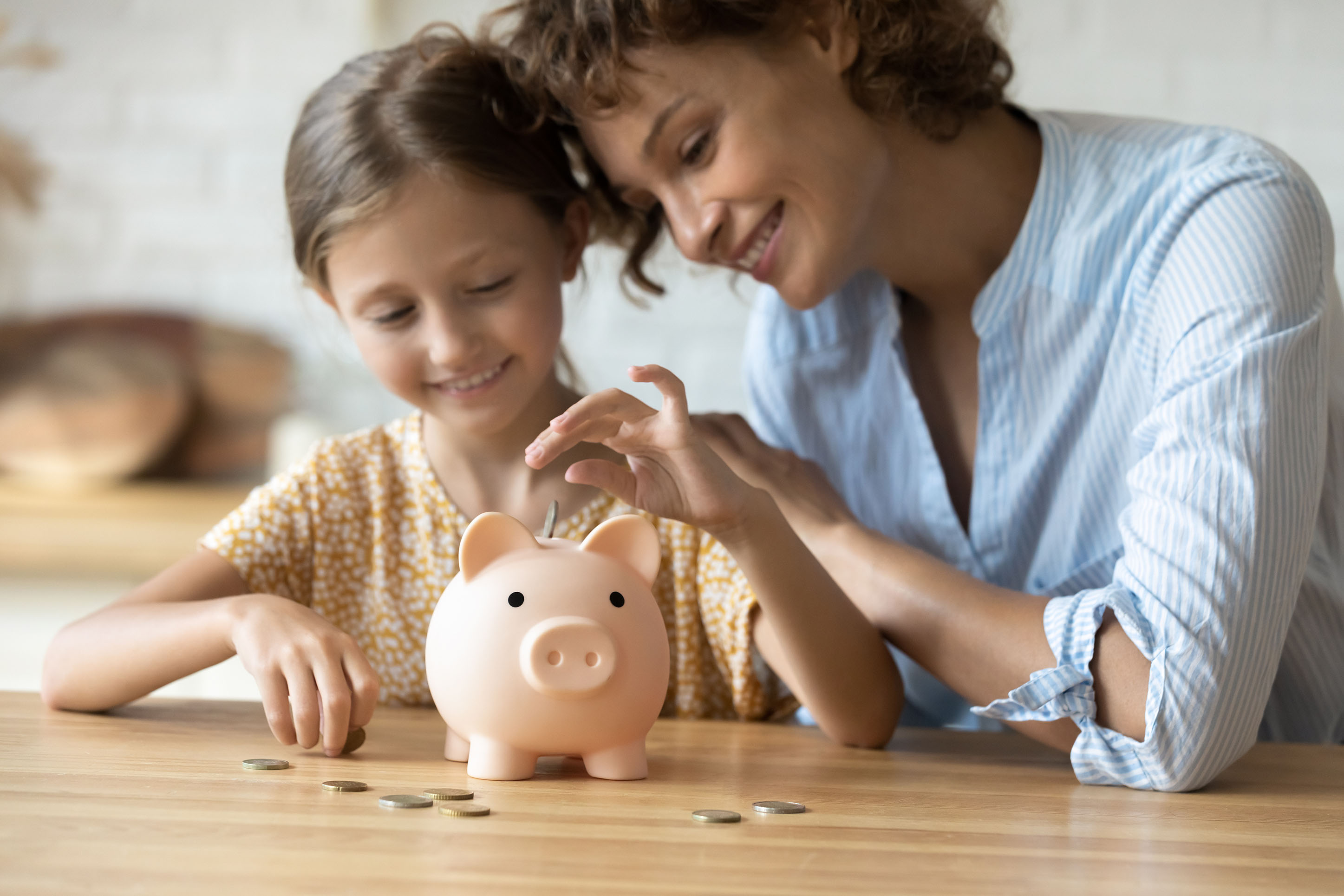 Mom and daughter putting money into a piggy bank. 