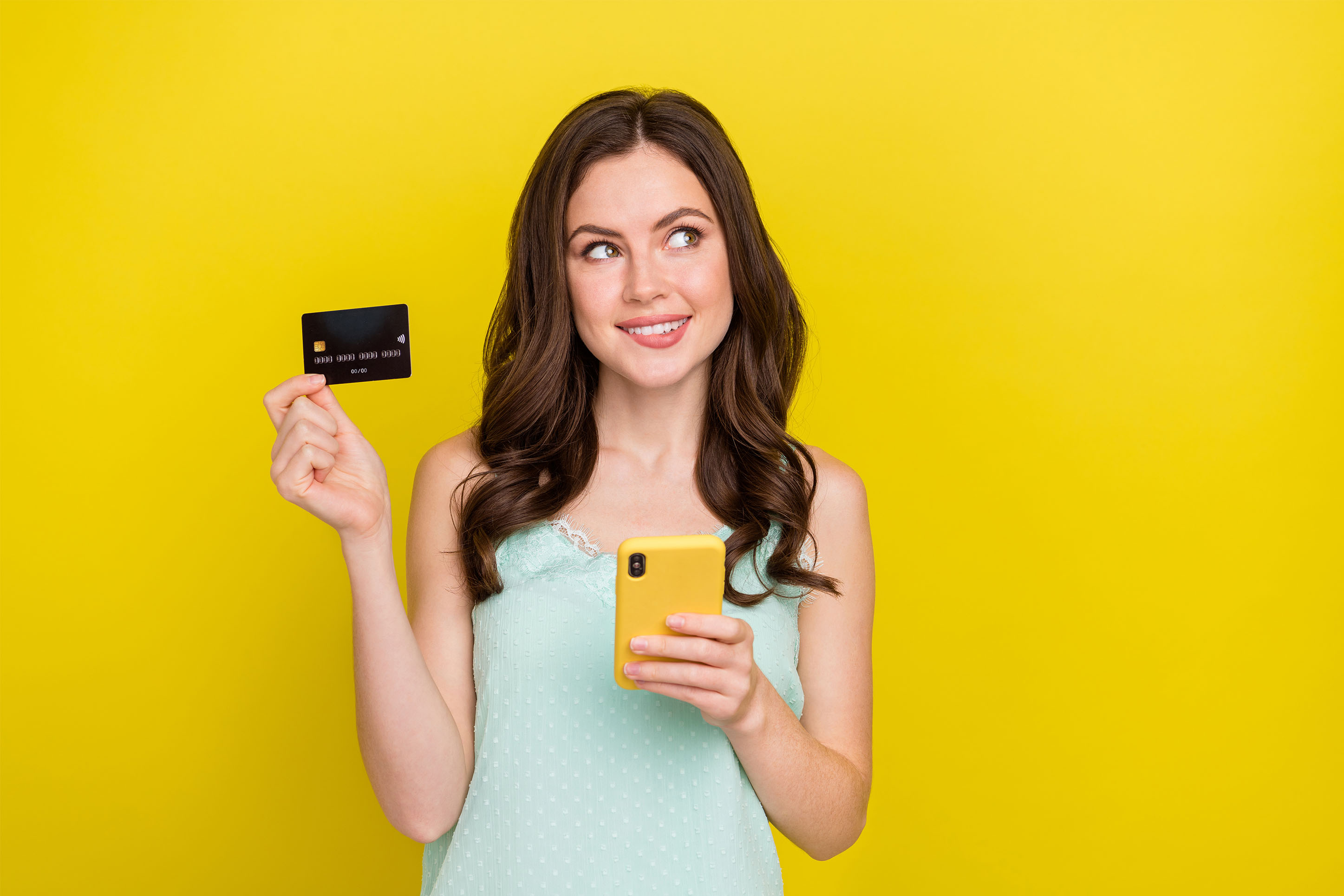 Woman with her credit card and mobile phone, monitoring her credit. 