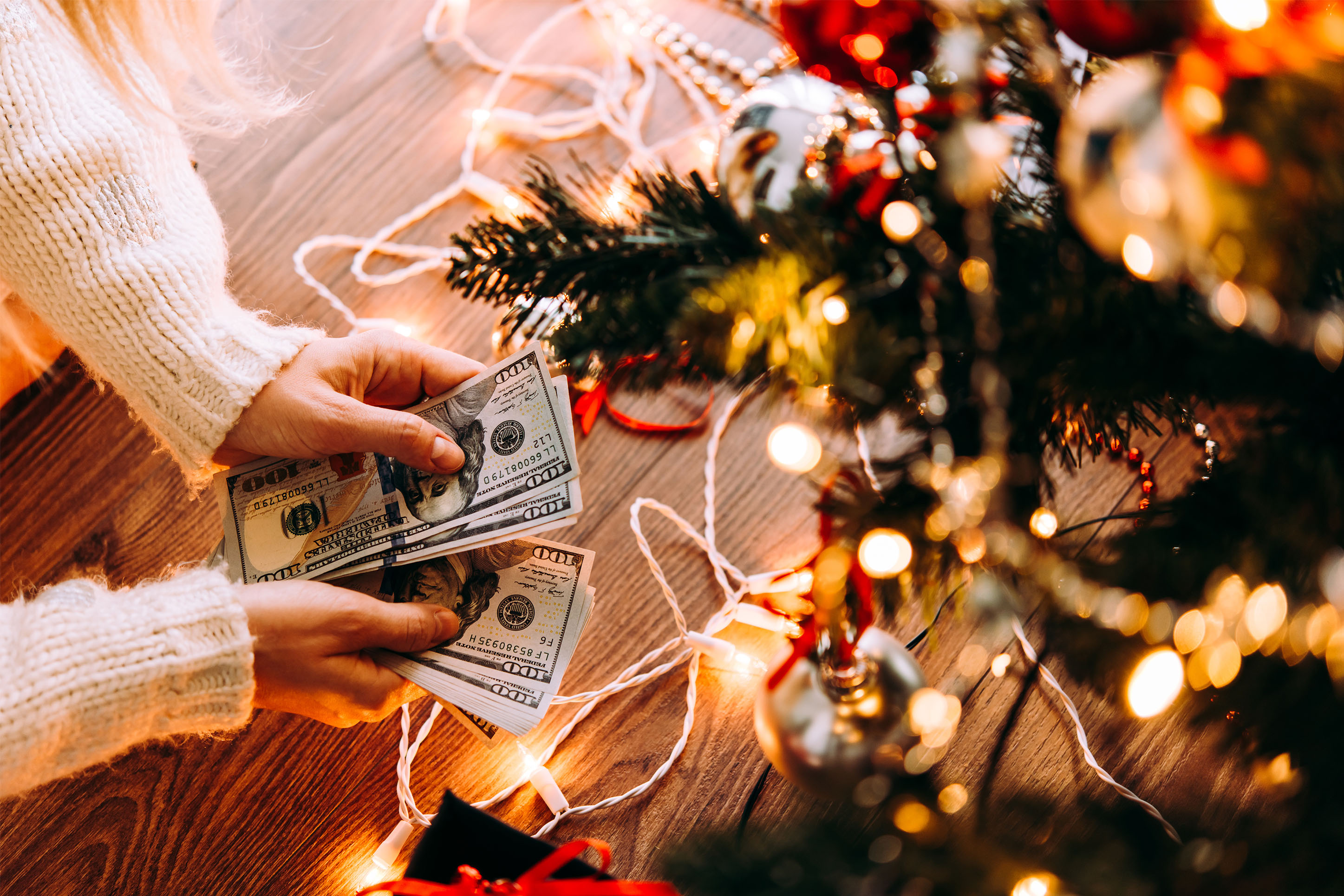 Photo of someone counting money next to a Christmas tree. 